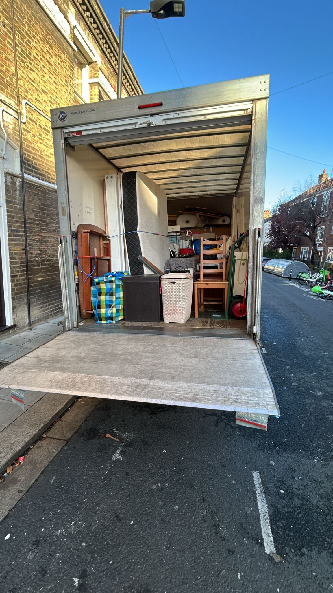 Professional house and flat removals crew loading a van carefully on a residential street near Colliers Wood retail area