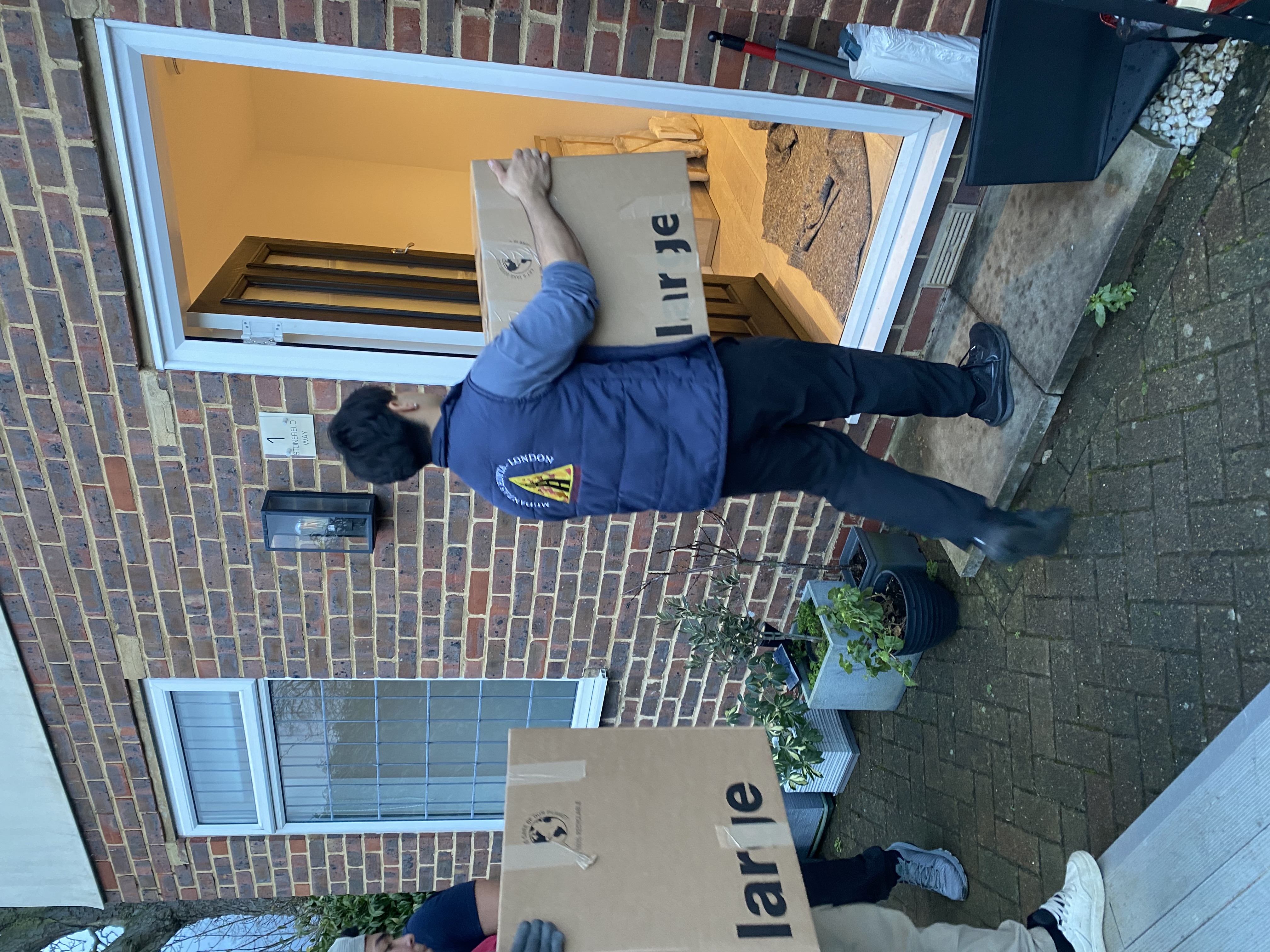 Loader carrying box inside house in Earlsfield SW18